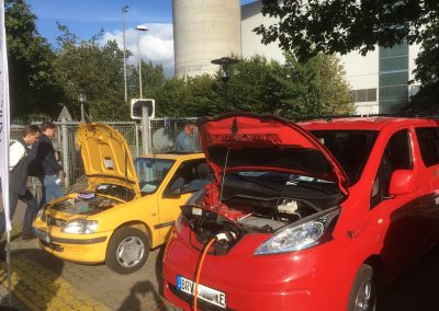 Ein gelber Elektro Oldtimer und ein roter Elektro Kleinbus mit geöffneter Motorhaube